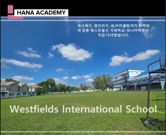 Green sports field and school buildings at Westfields International School under a blue sky